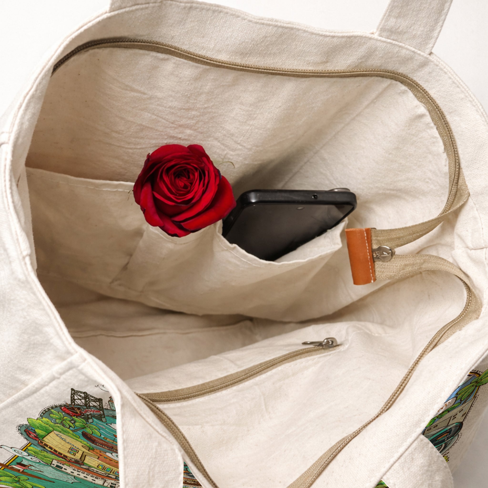 Open beige tote bag with a red rose and black phone inside, on a white background